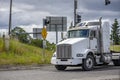 Classic bonnet white big rig semi truck tractor driving on the city crossroad with traffic light Royalty Free Stock Photo