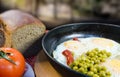 Classic breakfast. Fried eggs, peas, tomato and bread