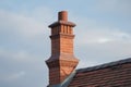 classic brick chimney with metal smoke deflector and stovepipe on a roof with wooden shingles