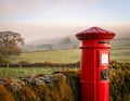 Classic British Red Post Box with a misty countryside backdrop Royalty Free Stock Photo