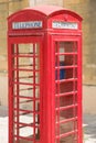 Classic British style of red, wooden telephone-box with blue phone inside