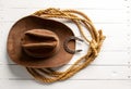 Brown cowboy hat lasso and horseshoe wild west still life on rough white wooden table