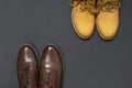 Classic brown leather men`s shoes and Yellow men`s work boots from natural nubuck on gray black background top view flat lay cop Royalty Free Stock Photo