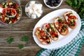 Classic bruschetta with tomatoes and feta on a white plate on a wooden background. Italian sandwiches with toasted baguette, goat Royalty Free Stock Photo