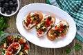 Classic bruschetta with tomatoes and feta on a white plate on a wooden background. Italian sandwiches with toasted baguette, goat Royalty Free Stock Photo