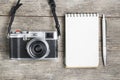 Classic camera with blank notepad page and gray pen on gray wooden, vintage desk