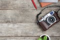 Classic camera on a gray wooden background, with a brown notepad, a red pen, a telephone and green growth. Concept list for a