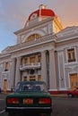 A classic car in front of an interesting building at Plaza Jose Marti Cuba during sunset