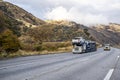 Classic car hauler big rig semi truck transporting cars on the semi trailer climbing uphill on the mountain highway road in Royalty Free Stock Photo