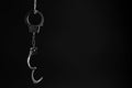 Classic chain handcuffs hanging on black background, space for text Royalty Free Stock Photo