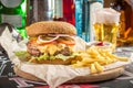 Classic cheeseburger with french fries and glass of beer on bar background Royalty Free Stock Photo