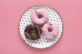 Classic chocolate, strawberry donut on white round plate with black peas isolated on pink background Flat lat lay Top View Royalty Free Stock Photo