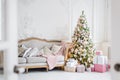 Classic Christmas light interior in white and pink tones with a couch, tree and molding in the Baroque style and