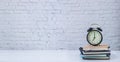 Classic clock on book stack with white brick wall texture background Royalty Free Stock Photo