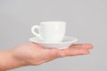 A classic coffee mug with a saucer stands on an open man`s palm