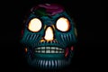 A classic colorful Mexican skull with bright orange eyes on a black background