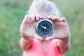 Classic compass in child`s hands on green grass background as symbol of tourism with compass, travel with compass and outdoo
