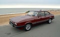 Classic Dark Red Ford Capri Motor Car parked on seafront promenade.