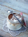 Classic delicious italian cheese dessert Tiramisu in glass jar on light wooden background.