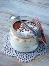 Classic delicious italian cheese dessert Tiramisu in glass jar on light wooden background.