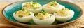 Classic Deviled Eggs Garnished with Fresh Chives and Black Pepper, Served on a Blue Plate Royalty Free Stock Photo