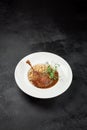 Classic dish french cuisine - roasted duck leg in porto sauce with garnish on black background. Cooked duck leg with pearl barley