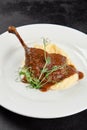 Classic dish french cuisine - roasted duck leg in sauce with garnish on black background. Cooked duck leg with mash potatoes on
