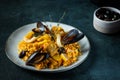 Classic dish of Spain, seafood paella in plate on blue background top view. Spanish paella with shrimps, clamps, mussels