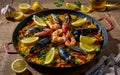 Typical spanish seafood paella in traditional pan. Vegetable paella with seafood on a wooden background Royalty Free Stock Photo