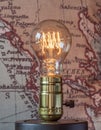 Classic edison light bulb with looping carbon filament on map ba
