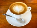 Classic foamy cappuccino in on a dark grained wood table. Detail. From above