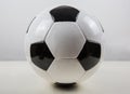 Classic football ball on the table, black and white pattern, isolated on grey background. Real, traditional soccer ball symbol