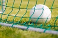 Classic football (soccer) ball on green grass ground at the back of the goal net Royalty Free Stock Photo