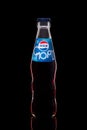 Classic glass bottle of soft drink Pepsi-Cola, on a black background. American multinational food and beverage company PepsiCo. Royalty Free Stock Photo