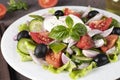 Classic Greek salad from tomatoes, cucumbers, sweet pepper, olives, basil and feta cheese on white plate Royalty Free Stock Photo