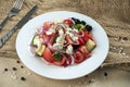 Classic Greek salad with tomatoes, onions, cucumber, feta cheese and black olives in white plate on a light background. Close up Royalty Free Stock Photo