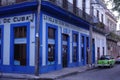 Classic green car in front of a vivid blue building