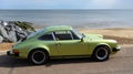 Classic Green Porsche motor car parked on seafront promenade sea in background. Royalty Free Stock Photo