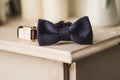 Classic groom accessories: blue bow tie and watch on a wooden table. Set of men's stylish vintage clothing. Male