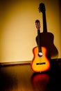 Classic guitar standing near wall under beam of light Royalty Free Stock Photo