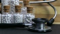 Classic Homeopathy Concept - Stethoscope and homeopathic medicine bottles consisting of pills on wood and dark background