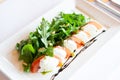 Classic italian appetiser of burrata cheese with tomato, and arugula rocket Royalty Free Stock Photo