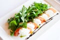Classic italian appetiser of burrata cheese with tomato, and arugula rocket Royalty Free Stock Photo