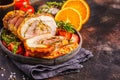 Classic Italian baked porchetta with oranges, copy space. Baked pork on dark background. Italian cuisine concept