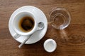 Classic italian single espresso in white cup, a milk jug and water isolated on brown wooden table from above. Royalty Free Stock Photo