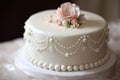 classic ivory ring cake with delicate pink flowers and pearl accents