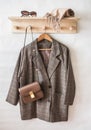 Classic jacket in english style, leather bag, sunglasses, cashmere scarf on a wooden hanger in a bright room Royalty Free Stock Photo