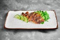 Classic Japanese sashimi set of raw eel with lime, cucumber on a white plate on a gray background. Close up, selective focus