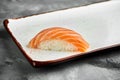 Classic Japanese sushi with raw salmon on a white plate on a gray background. Japanese cuisine. Close up, selective focus Royalty Free Stock Photo