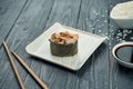 Classic japanese sushi rolls - gunkan with eel and spicy white sauce on a white ceramic plate on a black wooden background. Close Royalty Free Stock Photo